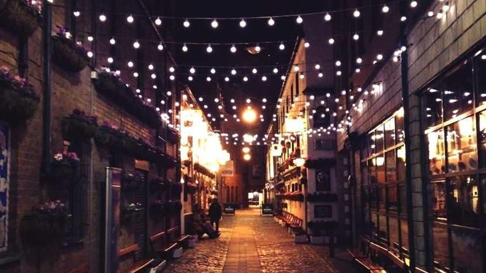 A black and white photographic film negative held up against a window light box showing a high-altitude reconnaissance image of a mountainous landscape with infrastructure visible in faint geometric patterns.