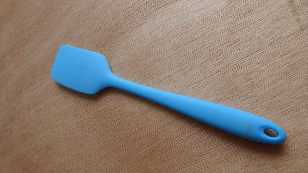 Spatule en bois et fouet m&eacute;tallique rang&eacute;s c&ocirc;te &agrave; c&ocirc;te dans un compartiment vide
