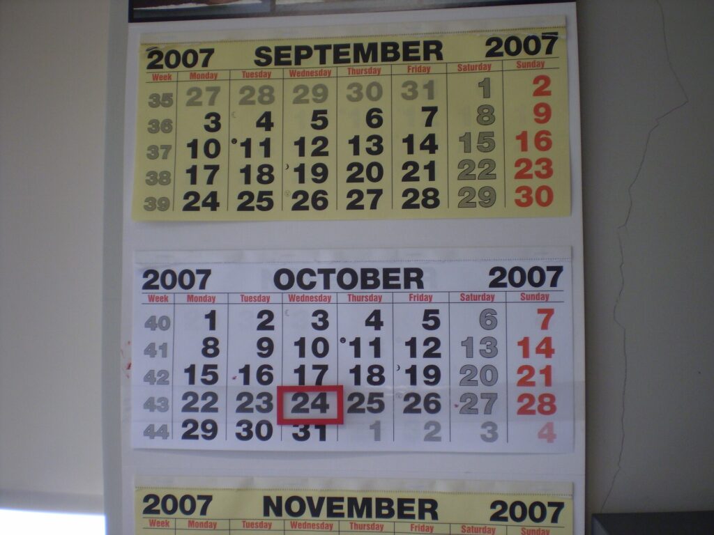 Calendrier mural annuel annot&eacute; au crayon, punais&eacute; au-dessus d'un plan de travail