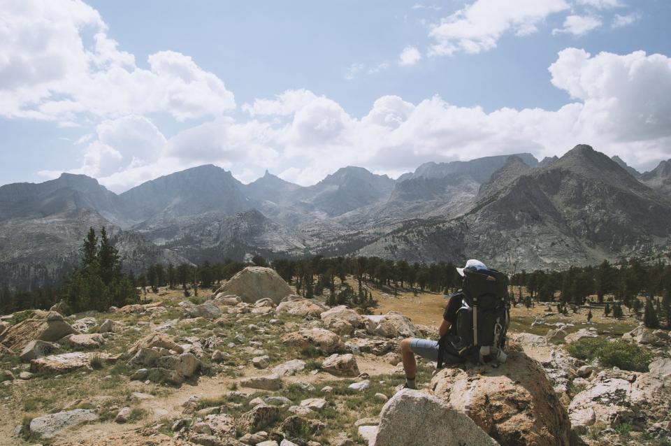 Sac &agrave; dos de randonn&eacute;e pos&eacute; au sol devant un sentier de montagne d&eacute;gag&eacute;
