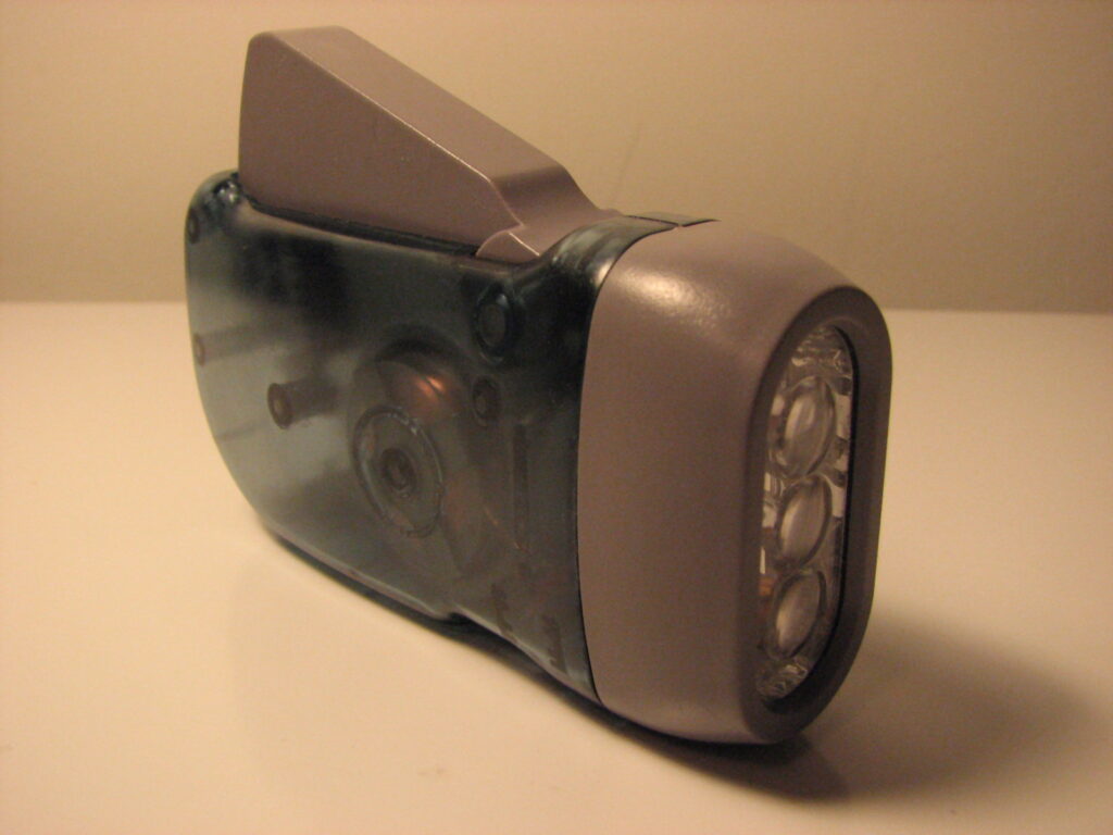 Lampe torche allum&eacute;e tenue &agrave; la main &eacute;clairant une charpente sombre