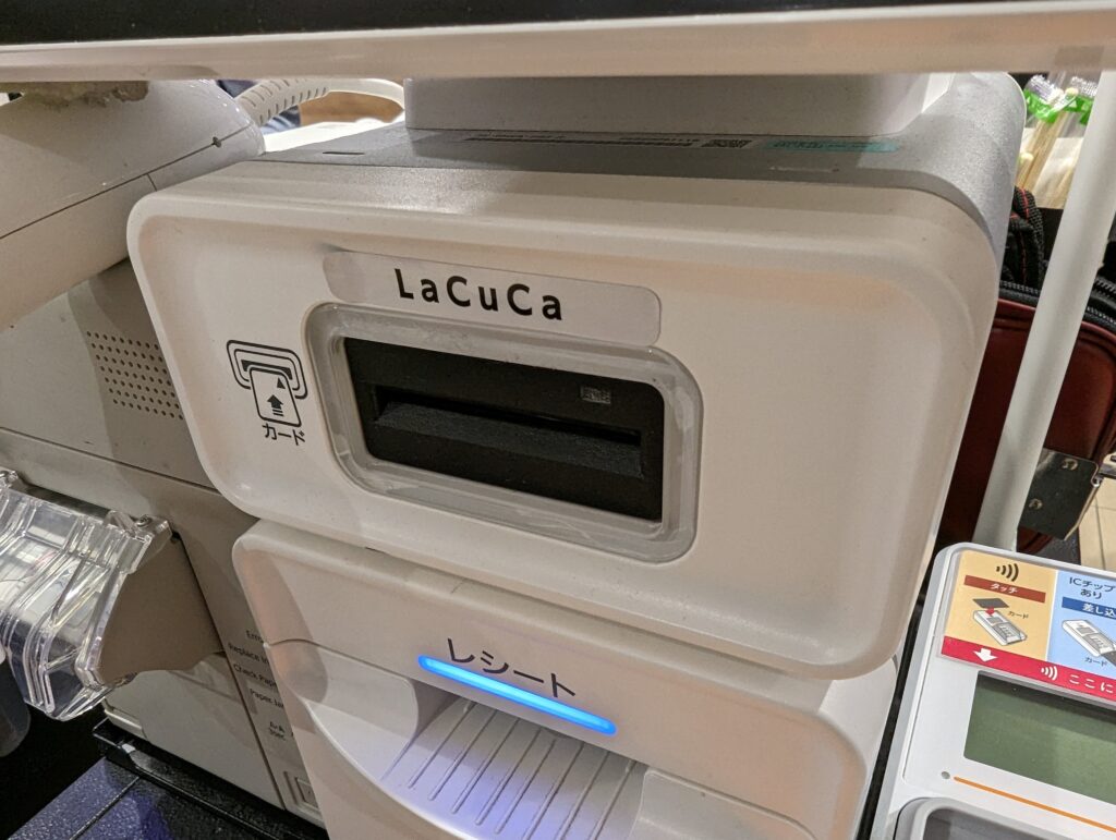 Terminal de paiement tenu à la main devant un comptoir de commerce de proximité