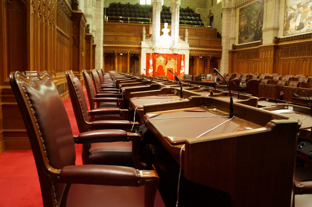 Hémicycle parlementaire vide, rangées de sièges et pupitres vus depuis le haut