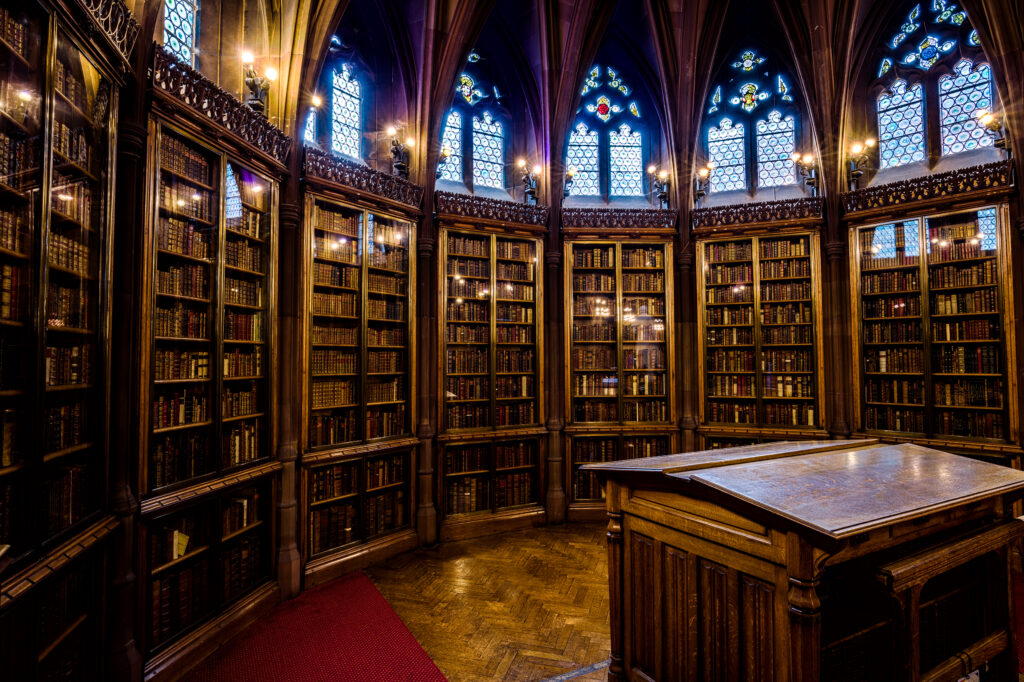 Salle de lecture d'une grande bibliothèque, tables alignées et rayonnages en hauteur