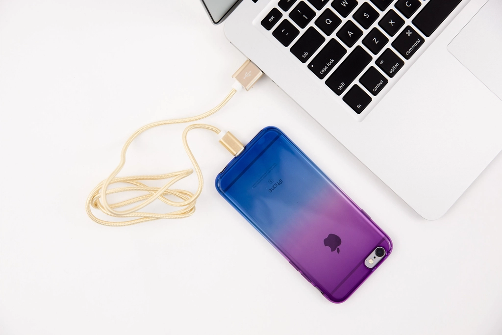 Câble de charge branché sur un téléphone posé au bord d'un bureau en bois